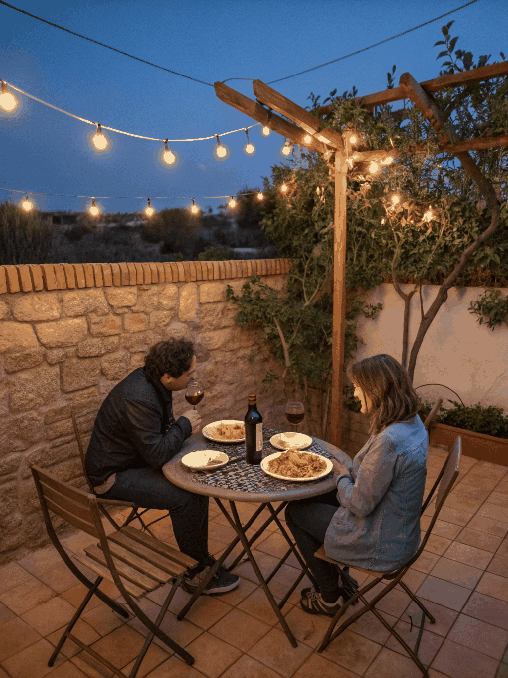 Outdoor riverside dining patio at sunset with warm string lighting